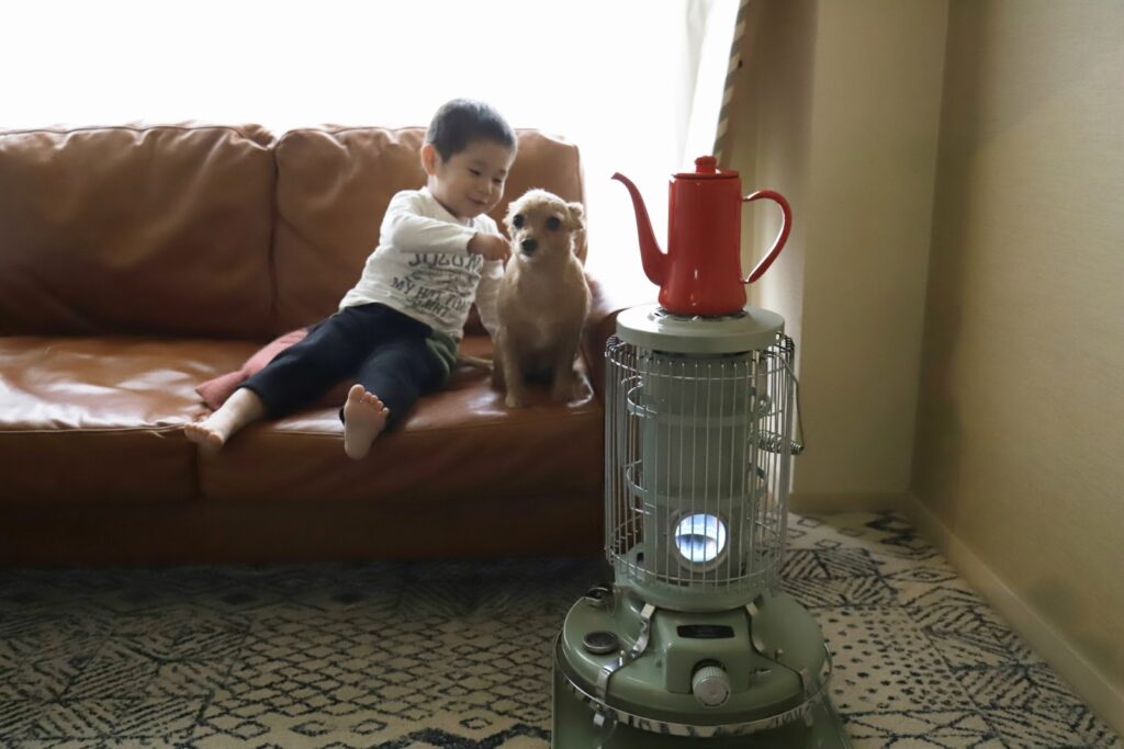 ストーブのある部屋の革張りのソファーに座る男の子を子犬